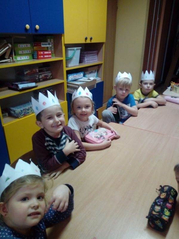 Zdjęcie przedstawia przedszkolaki w papierowych koronach na głowie podczas zajęć religii.