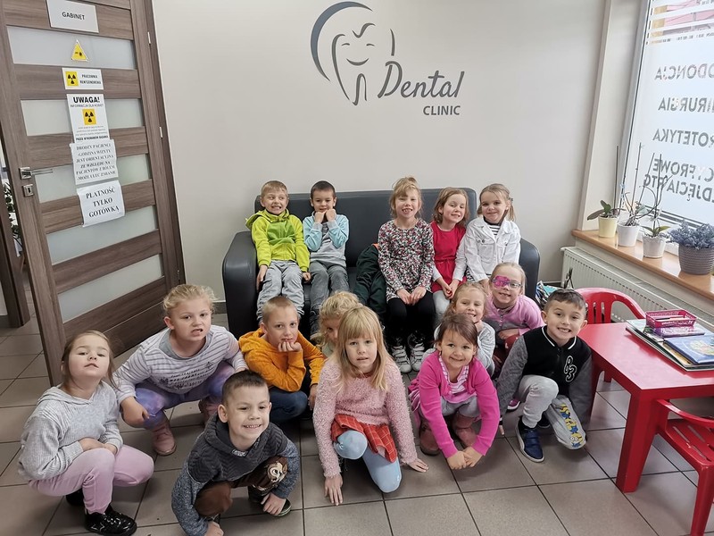 Dzieci z grupy Sówek znajdują się w gabinecie stomatologicznym, pozują do zdjęcia z pięknymi, zdrowymi zębami.