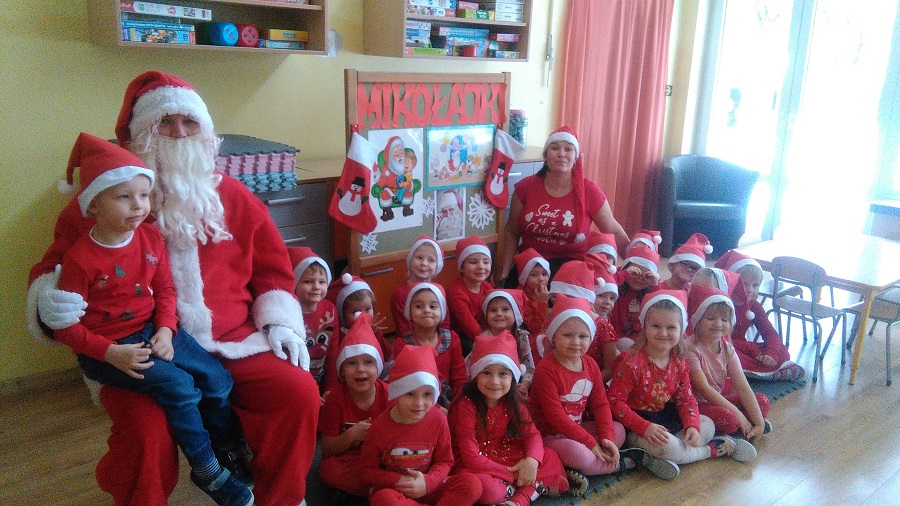 Grupa dzieci pozuje do zdjęcia z Mikołajek. Wszyscy ubrani są w przebrania św. Mikołaja.