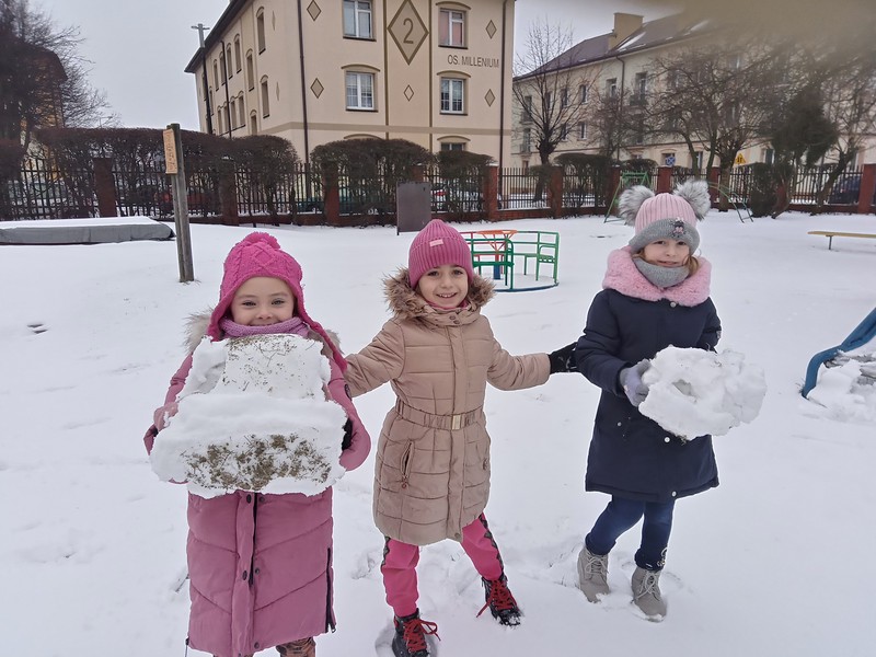 Dziewczynki w zaśnieżonym ogrodzie przedszkolnym.
