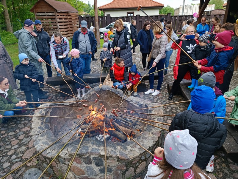 Dzieci i dorośli pieka kiełbaski przy ognisku