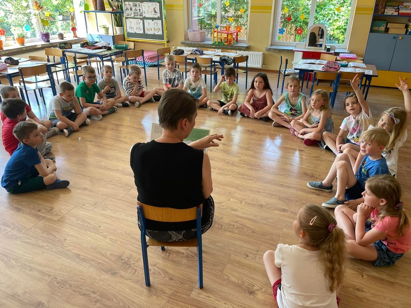 Dzieci siedzą w kole i słuchają książki o Żubrze Pompiku.