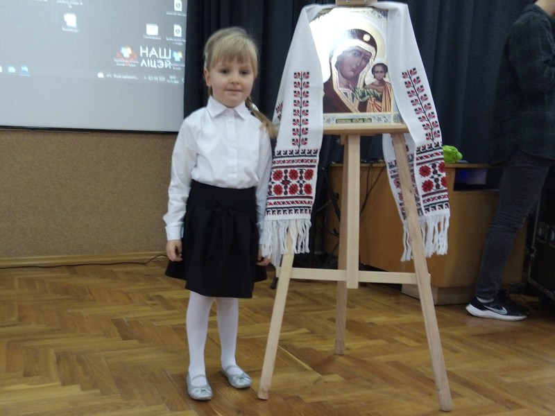 dziewczynka stoi przy ikonie