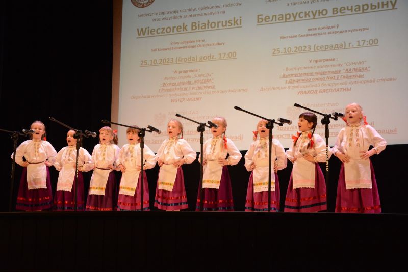 Grupa dziewczynek w ludowych strojach stoi na scenie grupy „Kolebka”.