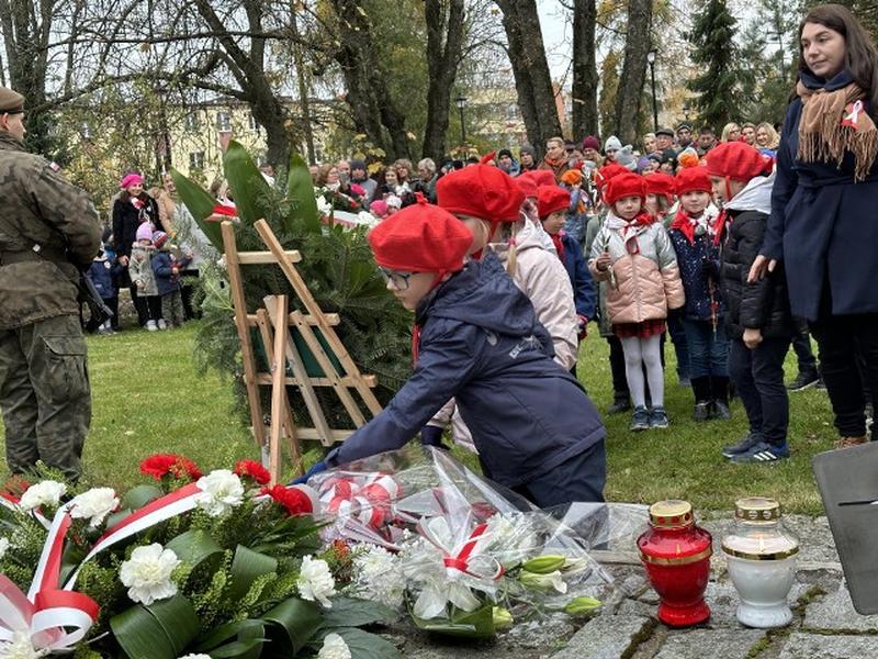 dzieci kładą kwiaty na pomniku